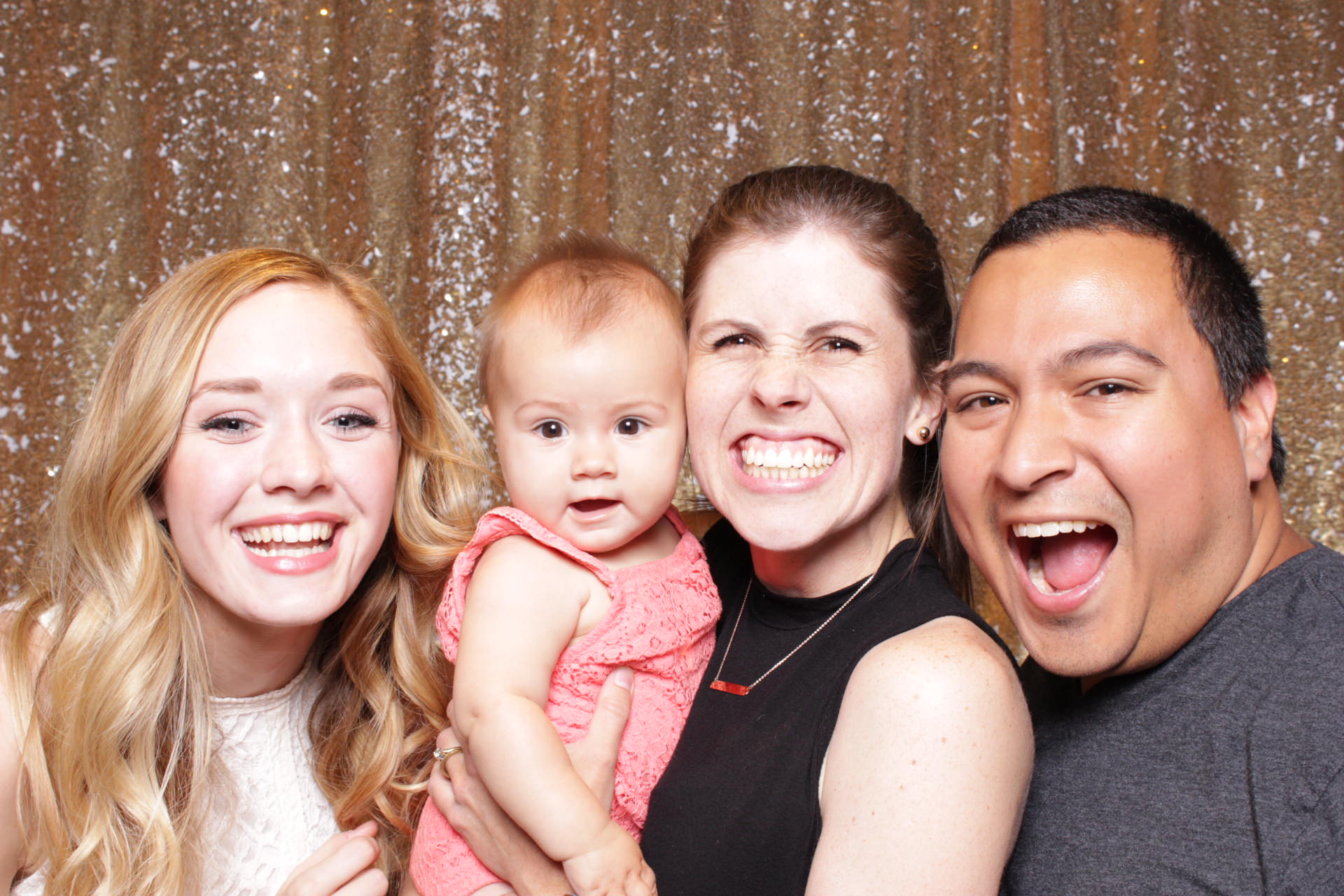 baby smiles with her parents in a photo booth