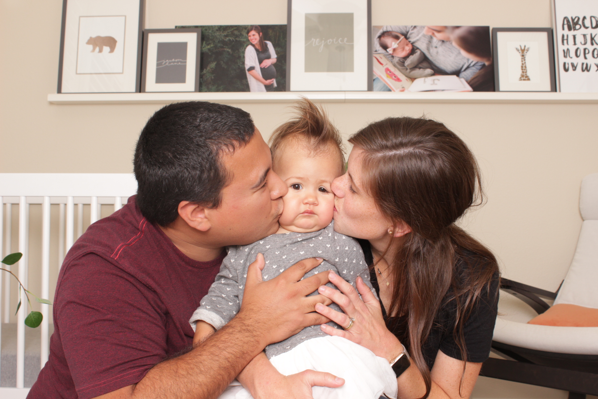 parents kiss baby at her first birthday party
