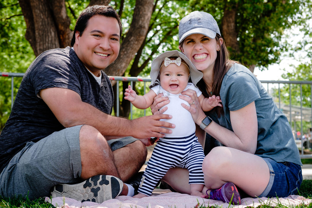 parents pose with baby at a picnic