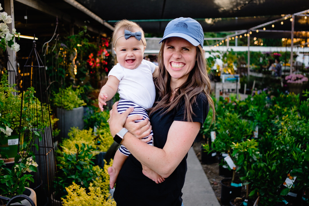 mom and baby smile together in a garden nursery