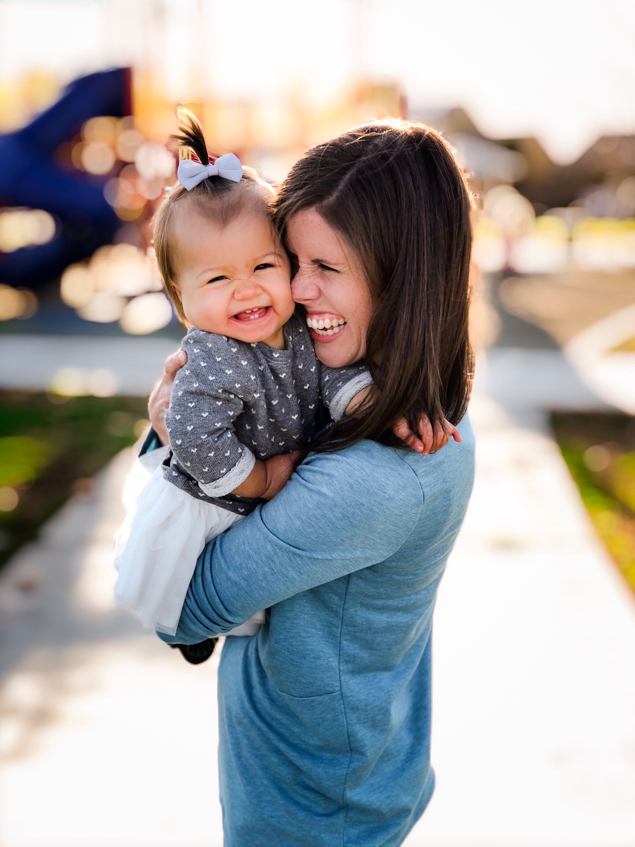 mom and baby laugh together at the park