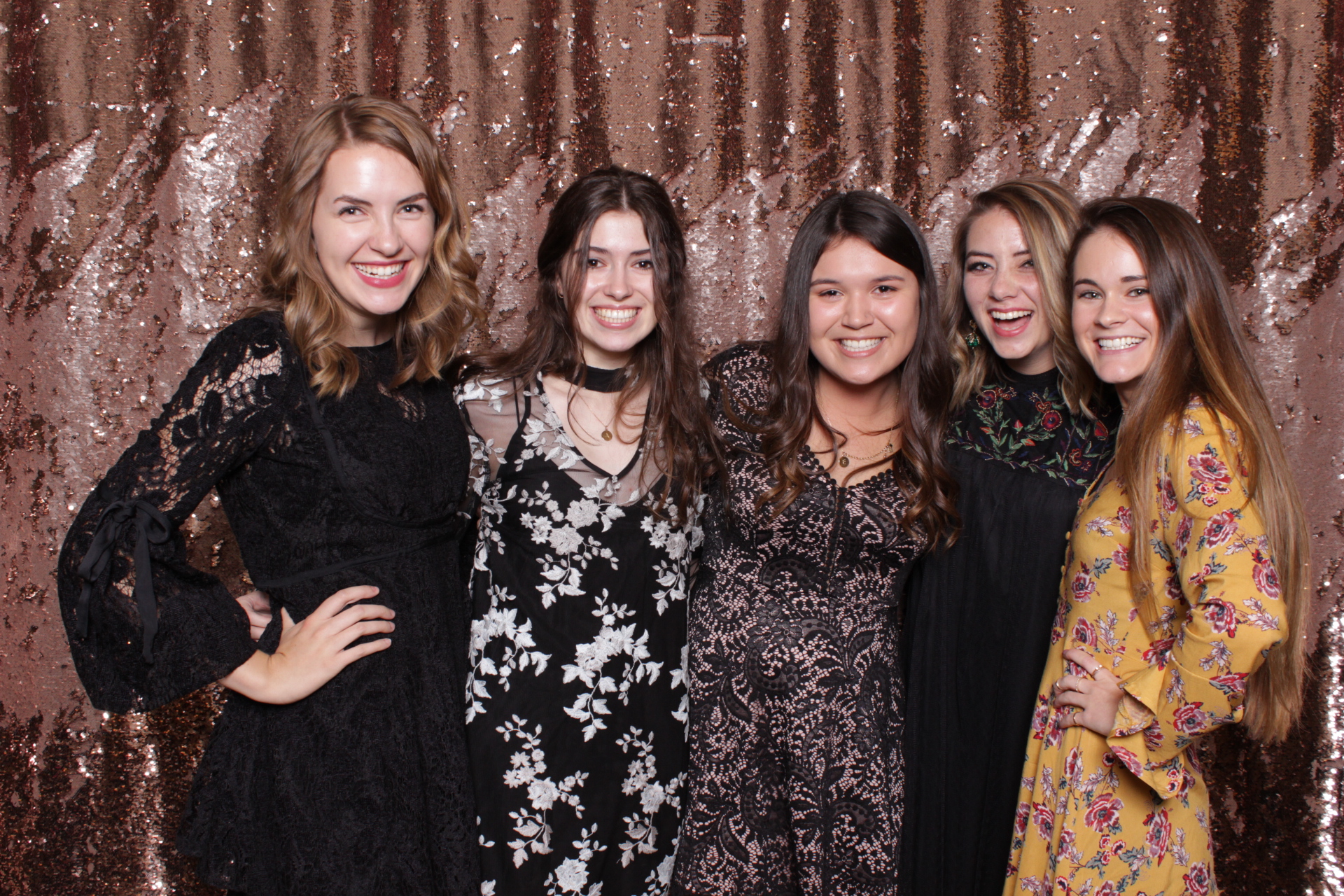 friends pose in photo booth with sequin backdrop